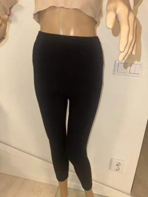 för gravida kvinnor - Säljer ett par svarta ribbade leggings med hög midja. De är stretchiga och sitter tight, perfekta till både oversized hoodies och crop tops. Materialet är mjukt och följsamt, vilket gör dem riktigt sköna att ha på sig hela dagen.