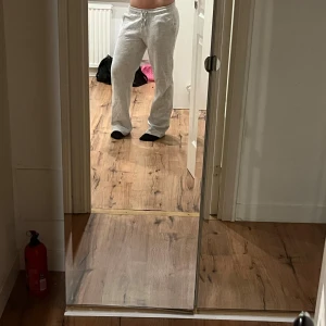 Grå mjukisbyxor med snörning - Säljer ett par ljusgrå mjukisbyxor med snörning i midjan. Byxorna har en loose passform och raka ben, perfekta för chill dagar. Tillverkade i mjukt bomullsmaterial som känns skönt mot huden. Enkla att matcha med hoodies eller t-shirts.