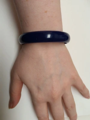 Mörkblå chunky plastarmband - Säljer ett chunky armband i mörkblå plast med rundad form. Armbandet är slätt och har en enkel, stilren look som passar till många olika outfits. Perfekt accessoar för dig som gillar färg och vill sticka ut lite extra. 21cm inre omkrets 