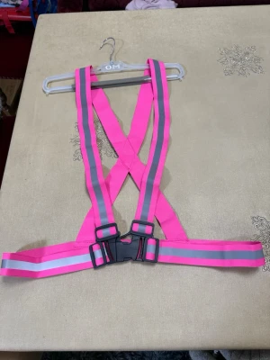 Reflexväst i neonrosa med spänne - Säljer en justerbar reflexväst i neonrosa med gråa reflexränder. Västen har ett brett spänne framtill och elastiska band som korsas i ryggen. Perfekt för att synas när du är ute och rör på dig i mörkret.