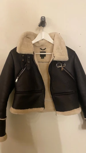 Svart pälsjacka från Boohoo - Säljer en svart pälsjacka från Boohoo med krage och detaljer i beige fuskpäls. Jackan har dragkedjor på båda sidorna, spänne vid halsen och långa ärmar med pälsdetaljer vid muddar och nederkant. Snygg och varm modell, säljer pga att den inte används. Använda ca 3 gånger💗 nypris-900