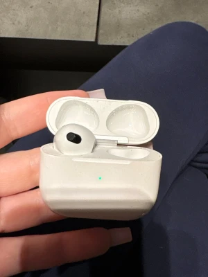 AirPods Pro 3 - Apple AirPods Pro med laddningsetui. Trådlösa hörlurar med aktiv brusreducering och bra ljudkvalitet. Etuiet har synligt yttre slitage, men hörlurarna ser ut att vara i gott skick. Finns bara en hörlur vänster.