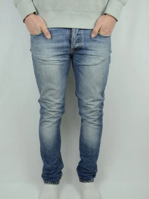 Nudie Jeans  - NUDIE JEANS  Storlek : W31 / L32  Modell : Grim Tim  Mått : A = 39,5CM - B = 108CM  Användning : Jeansen är i ett använt men fortfarande fint skick, se bilder  Nypris : Cirka 1800SEK  Modellen på bilden är 182CM och väger 76KG