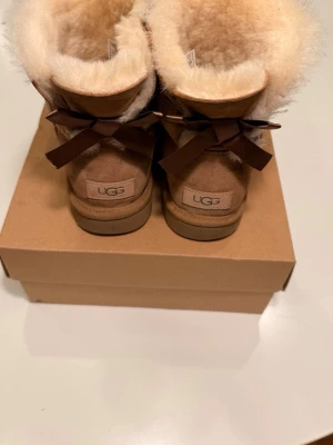 UGG boots bailey bow short ii - Super snygga UGG bailey bow chestnut, köpta  på vinted men jag trodde de var 39 och de är därmed för små. De är restorade till nästan nyskick (utom de defekter man ser)  enligt förra säljaren var de köpta bara några veckor sedan när jag köpte de, så jag skulle gissa tidig december sen november. priset diskuteras men jag satte det på 2k så ingen köpte direkt