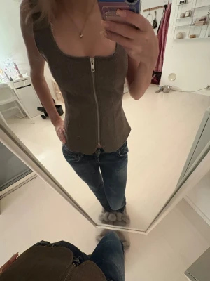 Brun korsettopp från Zara med dragkedja - Säljer en brun korsettopp från Zara i storlek S. Toppen har en snygg, figurnära passform och är gjord i ett mjukt material som liknar mocka. Dragkedja framtill och den är ärmlös med bredare band. Skriv om ni har frågor!💕