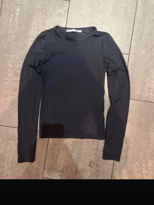 Marinblå långärmad topp från lager157 - En enkel marinblå långärmad topp från lager157 i storlek XS. Modellen är rak med rund halsringning och har en tight passform. Materialet känns mjukt och stretchigt, perfekt att styla till jeans eller kjol för en clean look. Under ena armhålan har sömmen sprättats upp lite