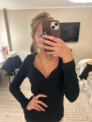 Svart ribbad långärmad topp - Säljer en svart långärmad topp med v-ringning och ribbad struktur. Materialet känns mjukt och stretchigt. 