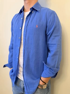 Blå linneskjorta Ralph Lauren - Nu säljer vi ännu en snygg polo skjorta som passar till alla tillställningar! Du ska kunna uttrycka stil utan att det kostar för mycket!🕺🍾💼🤩  Storlek👔: S Nypris💰: ca 1399kr