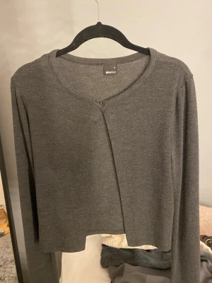 Grå kofta - Säljer en enkel och stilren grå kofta från Gina Tricot i storlek M passar S. Koftan har en croppad passform, rund halsringning och stängs med en knapp framtill. 😇