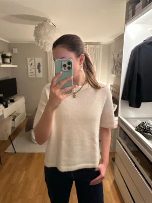 Vit stickad tröja från Gina Tricot - Supermjuk och stilren vit stickad tröja från Gina Tricot. Tröjan har korta ärmar, rund halsringning och ribbade kanter. Perfekt för lager-på-lager och funkar året runt till jeans eller kjol.