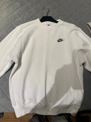 Vit sweatshirt från Nike XS - Säljer en clean vit sweatshirt från Nike i storlek XS. Tröjan har rund hals, lång ärm och en liten svart Nike-logga broderad på bröstet. Perfekt basic att ha i garderoben, tillverkad i mjukt material för extra komfort.