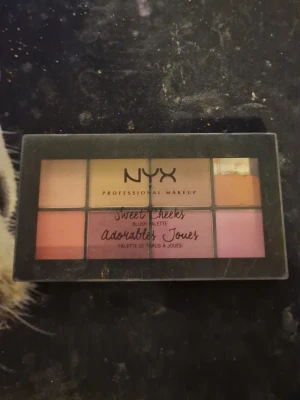 NYX Sweet Cheeks Rougepalett - NYX Sweet Cheeks Adorable Joues rougepalett med åtta olika nyanser i rosa, persika, guld och bruna toner. Paletten har en rektangulär plastförpackning med genomskinligt lock och är perfekt för att skapa olika blush-looks. Pudret är lätt att applicera och blanda.