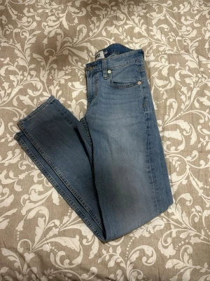 Blå jeans från Lager 157, storlek S - Säljer ett par klassiska blå jeans från Lager 157 i storlek S. Jeansen har fem fickor, gylf med dragkedja och knapp, samt raka ben. Materialet är jeans med snygga slitningar och ljus tvätt. Perfekt för dig som gillar enkel och tidlös stil.