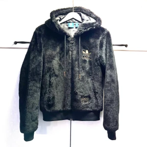 Exklusiv Adidas Hoodie Teddy Chile 62 , storlek S - En jacka/hoodie för alla adidas älskare. Svart Adidas jacka/hoodie med luva och dragkedja. Jackan har broderad Adidas logga framtill och "Adidas Teddy Chile 62" nedtill i guld färg. Den har två fickor med dragkedja på varsin sida."Jackan är ikonisk" Och engångs production svårt att få tag på.Teddyn har använts fåtal gånger och är i bra skick. Vänligen observera att jag inte har någon öppetköp.  Passar kvinnor och män Färg:Svart / Guld Skickar endast med PostNord.