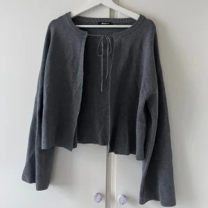 Grå kofta med snörning - Säljer en grå kofta från Gina Tricot med snörning framtill vid halsen. Koftan har långärmade och har lite vidare ärmar. 