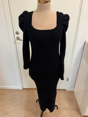 Svart ribbad långklänning Shein - Svart ribbstickad långklänning från Shein med markerade axlar och lång ärm. Klänningen har fyrkantig ringning och figurnära passform som framhäver siluetten. Perfekt för dig som gillar en stilren och trendig look.