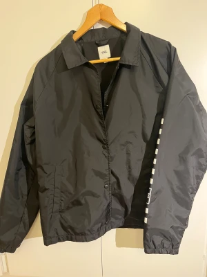 Svart coachjacka från Vans - Svart coachjacka i polyester från Vans. Den är i L men passar mer som M. Jackan är i superbra skick. Skriv om du har några funderingar, priset är diskuterbart!