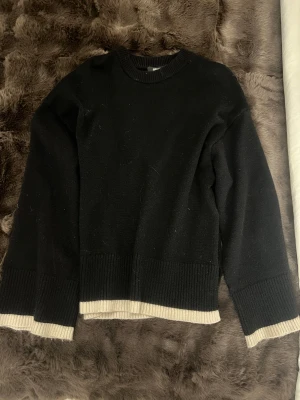 Svart stickad tröja med ljus beige rand  - Svart stickad tröja med ljus beige rand längst ner och längst ner på armarna tröjan är från Gina 