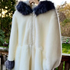 Vit Fuskpäls i vitt & grått med glitter spänne - Ny Superfin vit pälsjacka med fluffig huva och mörkgrå fuskpälsdetaljer i storlek 4XL Det är en rymlig modell ,utsvängd nertill och i armarna. Jackan har ett glittrande kristallspänne framtill och dragsko i midjan för snygg passform. Perfekt för dig som vill sticka ut under kalla dagar +att det är superinne med Fuskpäls i vinter ;-)