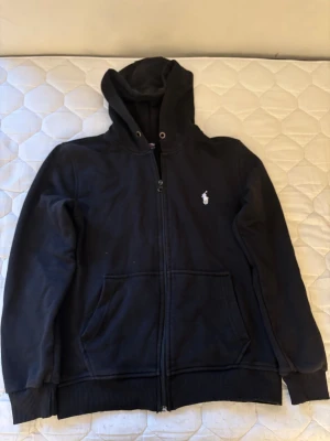 Svart POLO Sport hoodie - Svart Polo Sport-hoodie från Ralph Lauren med broderad logotyp. Verkar vara i gott skick med mindre spår av användning. Hoodien har inte snören.  ⭐️ Skick: 7/10 (Mindre tecken på slitage) 🎨 Färg: Svart 📦 Snabb och varsam frakt