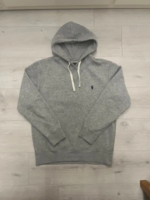 Ralph lauren hoodie grå - Hej! Säljer en Ralph lauren hoodie som är grå//passar för den som använder strl M//är 180 och höger 70 och den passar bra//fråga gärna! 