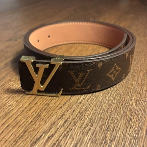 Brunt och guldigt bälte - Brunt och guldigt L&V bälte med mönster. 105 cm