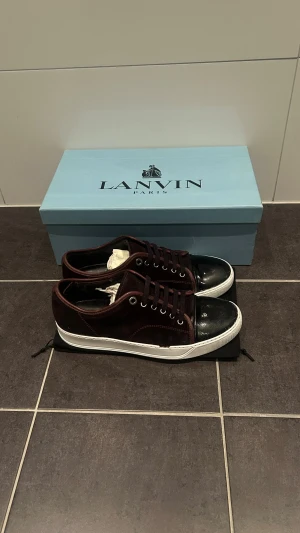 Lanvin vinröda sneakers med glans - Säljer mina snygga lanvin skor i färgen vinröd. Inget fel på dom utöver innuti skon men det märks knappt. Vill vara ärliga i mina annonser och det är en vit kräm på sulan. Man kan köpa det för typ 100 kr. Självklart får man med box och dust bag. Om ni har några frågor så fråga gärna. Priset är inte huggit i sten så kom med bud.