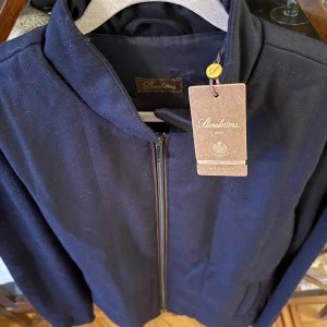 Stenströms jacka  - Snygg marinblå ull jacka från Stenströms med stilren ståkrage och hel dragkedja framtill. Jackan har ribbade ärmar och två diskreta fickor. Perfekt för dig som gillar minimalistisk design och vill ha något lätt och fräscht. Pris från butik ligger på 6000kr. 100% ull. 