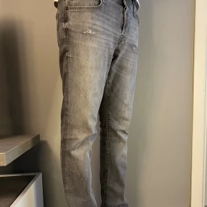 Jack & Jones Jeans Slim Glenn – Grå  - Gråa jeans från Jack & Jones, modell Slim Glenn med lätt slitna detaljer för en snygg vardagslook. Storlek: 29/32 | Skick: Nyskick – inga hål, fläckar eller missfärgningar | Material: Stretchig denim, bekväm och formstabil.