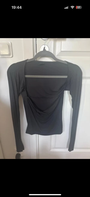 Svart långärmad topp med öppen rygg - Säljer en svart långärmad topp från NA-KD med snygg öppen rygg och draperad detalj baktill. Toppen är tight i passformen och gjord i mjukt, stretchigt material som sitter skönt mot kroppen. Perfekt för dig som gillar minimalistisk stil med en twist.