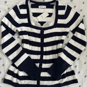 Randig babydoll kofta från Hollister, marinblå/vit - Superfin helt ny babydoll kofta från Hollister i marinblått och vitt med breda ränder. Tröjan har lång ärm, knappar hela vägen och en fyrkantig urringning. Stickad i mjukt material och har ribbade muddar. Perfekt för lager-på-lager och snygg till jeans. Spetslinne ingår ej. 