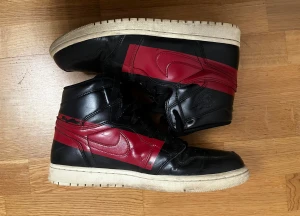 Unika Jordan 1 high - Säljer ett par Air Jordan 1 High OG ”Defiant Couture” från 2019. En sällsynt modell med unik design där Swoosh-märket på sidan har varsin framträdande röd “målarfärgs”-detalj. Skorna är tillverkade i premiumläder och sparsamt använda. Originallådan medföljer ej. Ett par crease-skydd (2 st) medföljer. Perfekta för vinterbruk eller samling.
