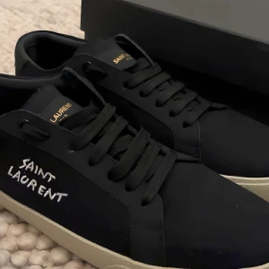 Svarta Saint Laurent sneakers  - Säljer ett par svarta YSL-skor i fint skick. Jag är inte helt säker på äktheten, därför säljs de till ett lågt pris. Skorna är stilrena, bekväma och passar både till vardag och fest. Endast sparsamt använda. ALLT INGÅR 
