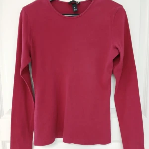 Långärmad tröja med rund halsringning - En stilren rosa långärmad tröja med rund halsringning. Tillverkad i bomull. Perfekt att matcha med jeans eller kjol för en clean look. Tröjan har naturligtvis tvättats. Se bilder för skick och passform. Armhåla till armhåla är cirka 42 cm. Axelsöm till ärmslut är cirka 59 cm. Tvättas i 40 grader.