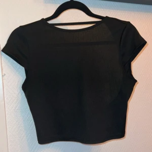 Svart croppad topp med öppen rygg - Säljer en svart croppad topp med korta ärmar och en öppen rygg. Toppen är i storlek M och använd fåtal gånger 