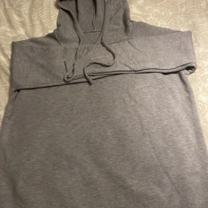 Grå kashmire hoodie  - En enkel och stilren grå hoodie med huva och snörning framtill. Tröjan har långärmade raglanärmar och ribbad nederkant. Perfekt för chill dagar och passar till det mesta. Materialet känns mjukt och bekvämt mot huden.