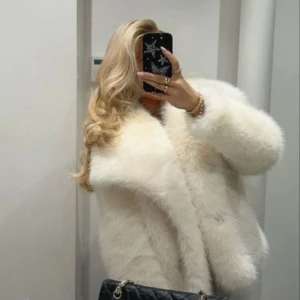 Vit fluffig pälsjacka från ZARA - Supermysig vit pälsjacka från ZARA med bred krage och långärmad modell. Jackan har en oversized passform och är tillverkad i syntetiskt pälsmaterial som ger en lyxig och trendig vibe. Perfekt för dig som vill ha en statement-jacka med extra fluff.