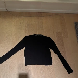 Svart v-ringad tröja Black Label lager 157 - Svart långärmad tröja från The Black Label Collection i storlek M. Tröjan har v-ringad hals och ett diskret ribbat mönster på framsidan. Enkel och stilren design som funkar till många olika looks. Från lager 157