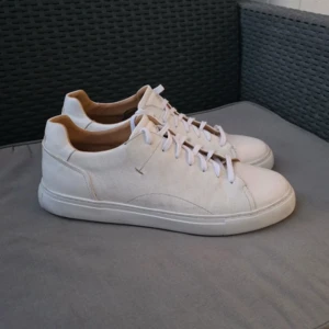 Madini Sneakers - Snygga sneakers i vitt skinn från Novita Man. Skorna är fodrade med mjukt kalvskinn och har uttagbara innersulor för extra komfort. Platta, vaxade skosnören och en ljus sula ger en stilren och fräsch look. Skorna är i storlek 45 och använda i bara en timme.