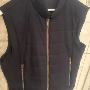 Mörkblå quiltad dunväst från Stenströms - Mörkblå dunväst från Stenströms med quiltad design och ståkrage. Västen har två praktiska fickor med dragkedja och en stilren look. Perfekt att slänga över en hoodie eller tröja för extra värme. Klassisk svensk kvalitet.