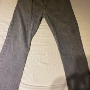 Gråa Armani Jeans straight fit - Snygga gråa jeans från Armani Jeans med klassisk femficksdesign, raka ben och diskreta gula sömmar. Bakfickan har metallogo och framfickan har en röd detaljsöm. Jeansen har bälteshällor och knappgylf. Perfekta för dig som gillar stilrena och tidlösa jeans.