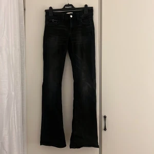 Svarta bootcut jeans från Gina Tricot - Svarta jeans från Gina Tricot i storlek 164. Modellen har bootcut-ben och klassisk femficksdesign med silverfärgade knappar bak. Jeansen är tillverkade i ett jeansmaterial med lätt tvättad look och normal passform.