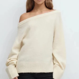 Offshoulder stickad beige tröja - Supermysig stickad tröja i beige med offshoulder-design och bred ribbad kant vid ärmslut och nederkant. Perfekt för dig som gillar en chill och snygg look med lite extra attityd. Långärmad och loose passform för maximal komfort.
