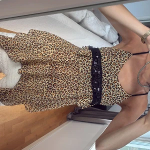 Leopardmönstrad linne paljettdetalj - Snygg linne med leopardmönster och tunna axelband. Linnet har en svart spets- och paljettdetalj i midjan som ger extra edge. Fladdrigt tyg och figurnära upptill, perfekt för dig som vill sticka ut.