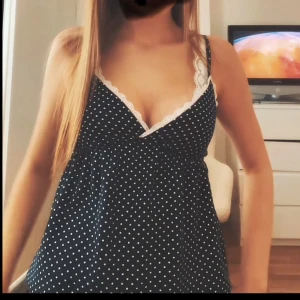 Svart prickig linnetopp med spets - Supersöt svart linnetopp med vita prickar och v-ringning. Toppen har tunna axelband och vit spetskant längs urringningen. ENDAST andvänd 1 gång hemma. 🫶🥹💞