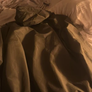 Grön vindjacka från Ellesse med huva - Säljer en grön vindjacka från Ellesse med stor logga på bröstet och praktisk huva med snörning. Jackan har half zip framtill och är tillverkad i syntetmaterial som står emot vind. Perfekt för dig som gillar sportig stil och streetwear.