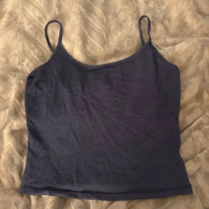 Mörkblå linne - Säljer en enkel och stilren mörkblå linnetopp från Shein i storlek L. Toppen har smala axelband och ärmlös design med rundad halsringning. Materialet är mjukt och lätt bomull, perfekt för varma dagar. Passformen är normal och toppen är enfärgad utan mönster.