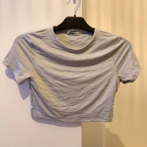 Ljusgrå croppad t-shirt från Sisters Point - En stilren ljusgrå croppad t-shirt från Sisters Point. T-shirten har rund halsringning och korta ärmar, perfekt för en enkel och clean look. Tillverkad i mjuk bomull som känns skön mot huden.