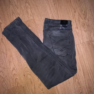 Replay anbass gråa jeans, storlek 30/32 - Snygga gråa Replay jeans i modell Anbass med smal passform. Jeansen har klassisk femficksdesign, svarta sömmar och Replay-logga på bakfickan. Tillverkade i stretchigt bomullsmaterial för extra komfort.