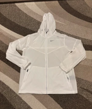 Nike vit vindjacka/springjacka - Säljer denna vindjacka/springjacka då den är för stor mig. Den är helt ny aldrig använd och är super skön att ha på sig. Vid frågor är de bara att skriva.